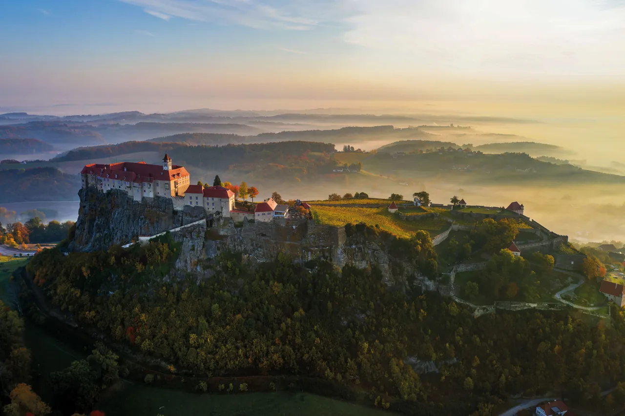Die Riegersburg über dem nebligen Hügelland im Morgenlicht