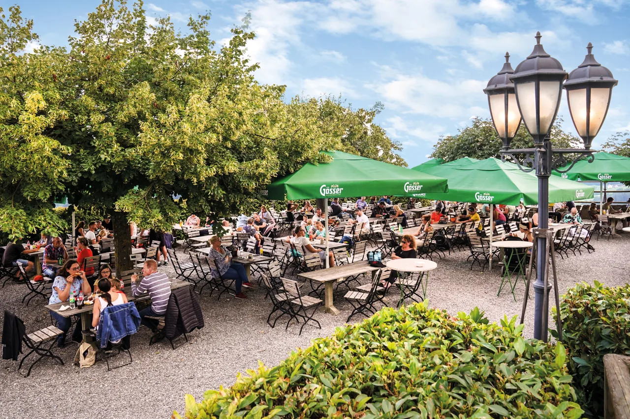 Der Gastgarten der Burgtaverne unter grünen Sonnenschirmen